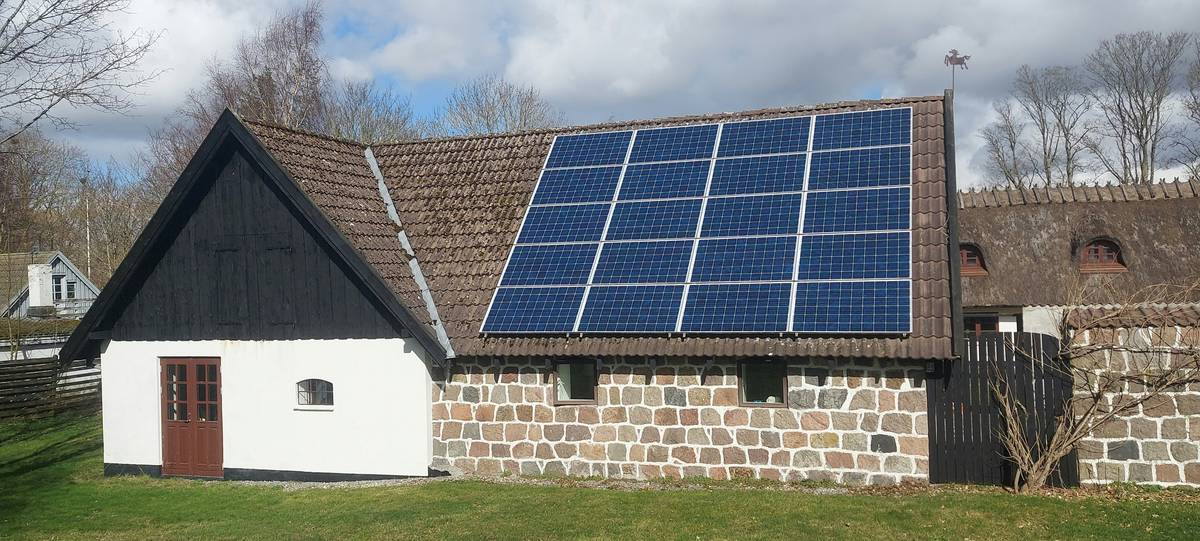 Technician spraying water on rooftop solar panels to demonstrate putting in solar panels benefits